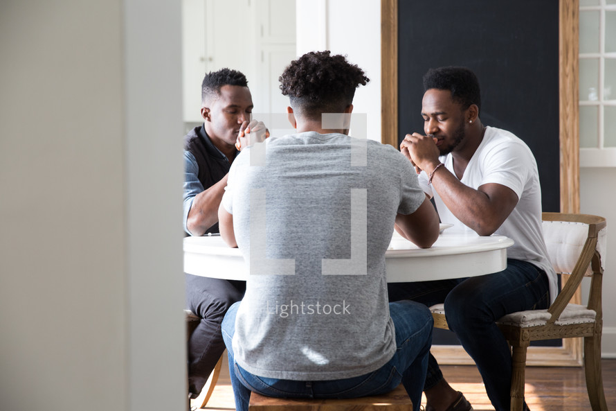 Group of friends in prayer around a table.
