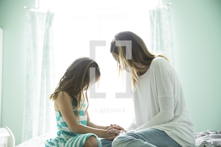 a mother and daughter praying together 