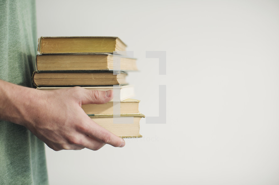 man holding a stack of books 