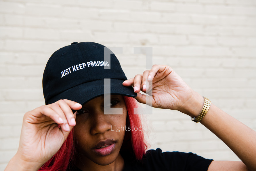 portrait of a young African American woman with Just Keep praising hat 