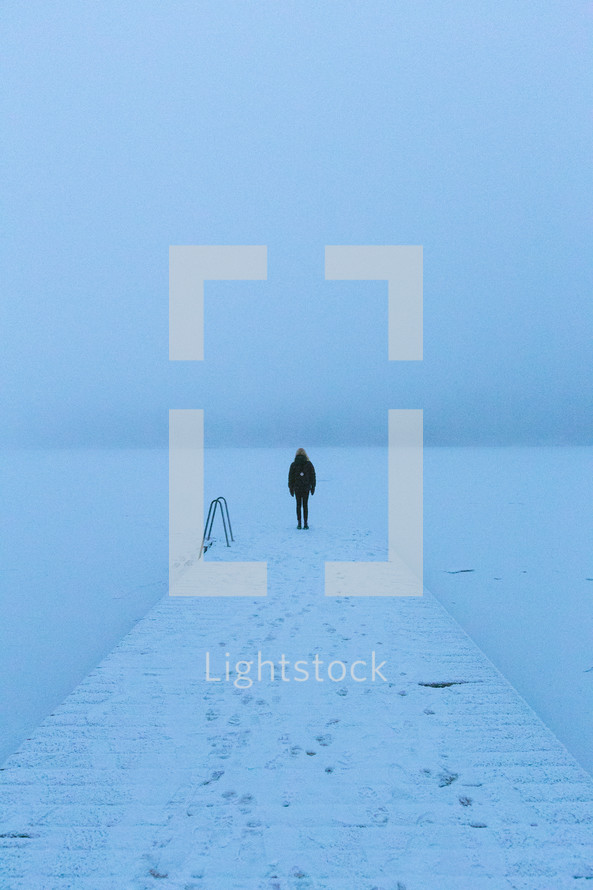 standing at the end of a snowy dock on a frozen lake 