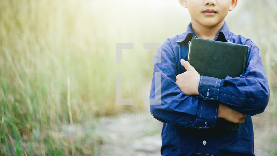 child holding a Bible close to his chest 