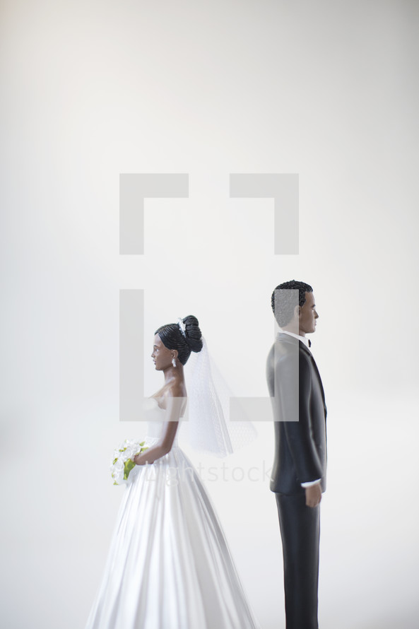 bride and groom figurines standing back to back 
