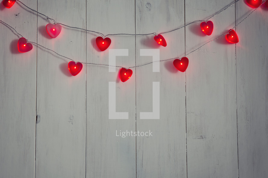 String of heart-shaped lights on a white wood background.