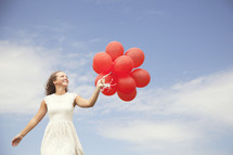 teenage girl walking and holding red balloons
