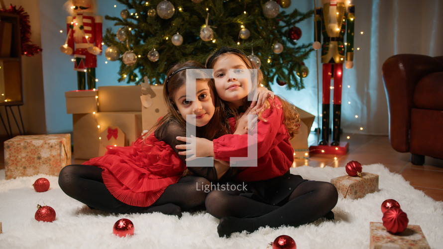 Young ladies playing and hugging under the Christmas tree 