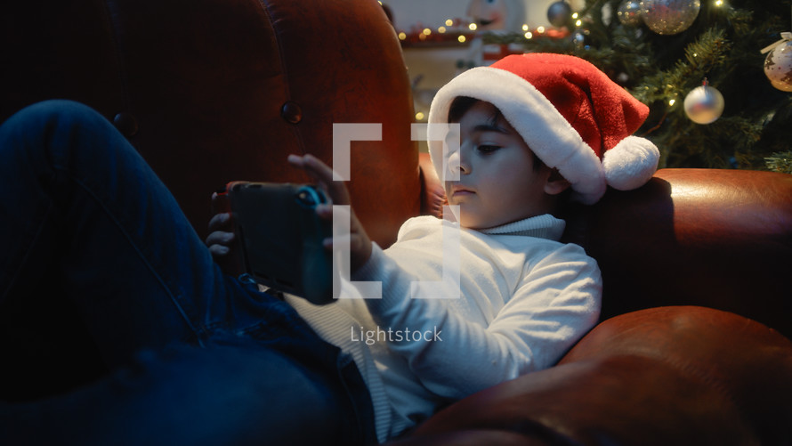 Little boy with Christmas hat playing videogame