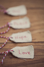 Christmas gift tags on a wood grain background, the first one reading "Love."