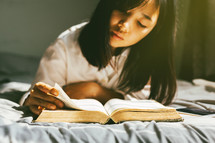 a girl reading a Bible in bed 