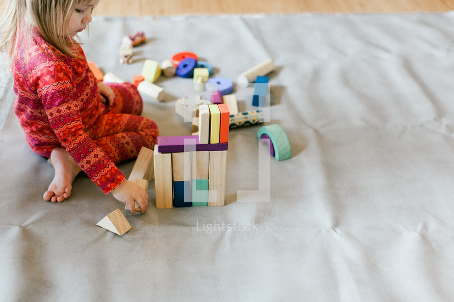 a toddler girl playing with building blocks 
