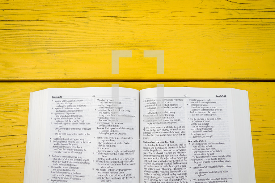 pages of an open Bible on a yellow table 