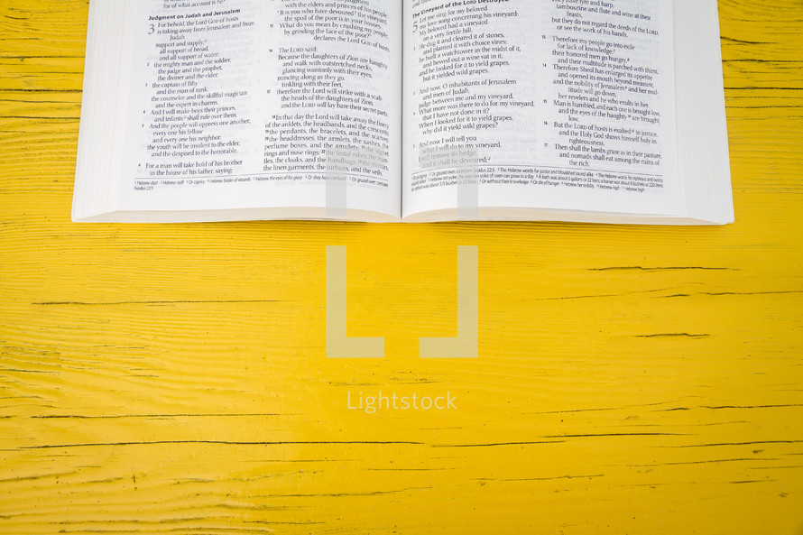 pages of an open Bible on a yellow table 