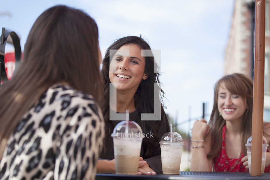 friends sitting at an outdoor table drinking milkshakes 