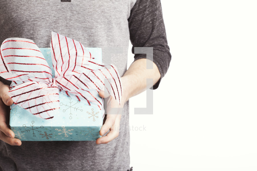 A man holding a blue wrapped gift with a red and white bow