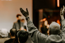 Elder man with his hand's raised during worship.
