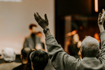 Elder man with his hand's raised during worship.