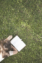 girl reading a Bible in the green grass