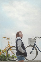a young woman standing beside bicycles 