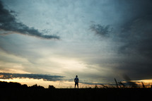 a man standing outdoors at sunset alone. 