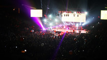 Audience bouncing balls through spotlights during a concert on stage.