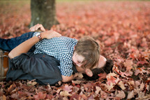 a father and son lying in leaves 