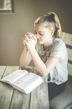 a girl reading a Bible and praying 