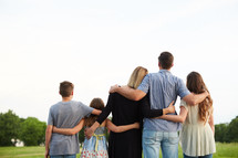 a family standing with arms around each other 