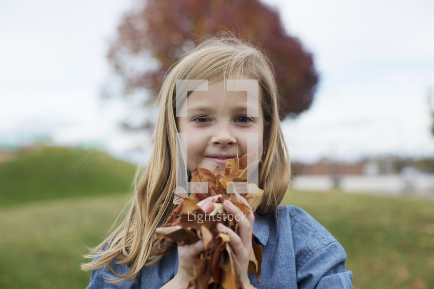 a girl holding fall leaves 