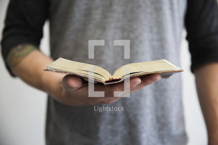 A man holding an open book in one hand.