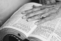 An elderly woman's hand on an open Bible.