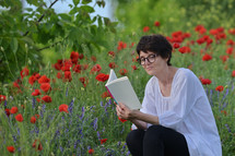 a woman reading a Bible in a field of flowers 
