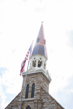 American flag in front of a steeple 