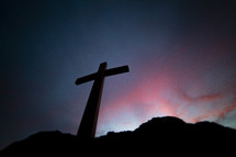 a silhouette of a cross at sunset 