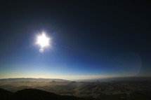 A sunburst over a mountain range. 