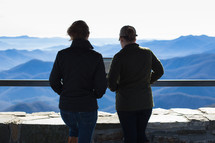 people looking over a railing at a mountain range 
