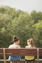 women sitting on a park bench talking 