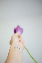 hand holding a tulip with love tattoo 