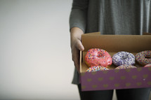 a woman holding a box of donuts