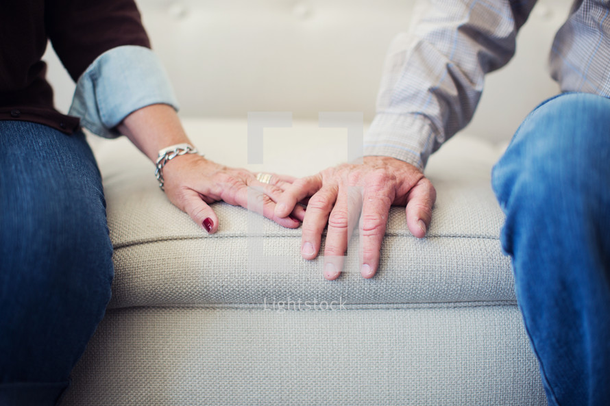 elderly couple touching hands 
