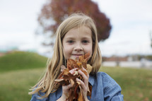a girl holding fall leaves 