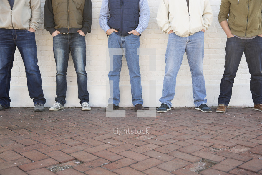 Men's group standing against a wall.