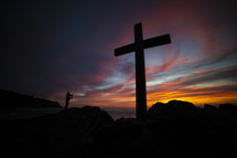 man fishing and a cross at sunset 