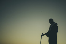 silhouette of a man in a robe and a walking stick
