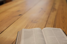 An open Bible on a wooden table