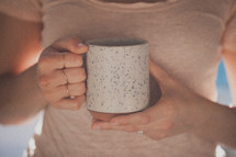 A woman's hands holding a white coffee mug