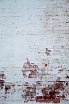 white paint peeling from a brick wall
