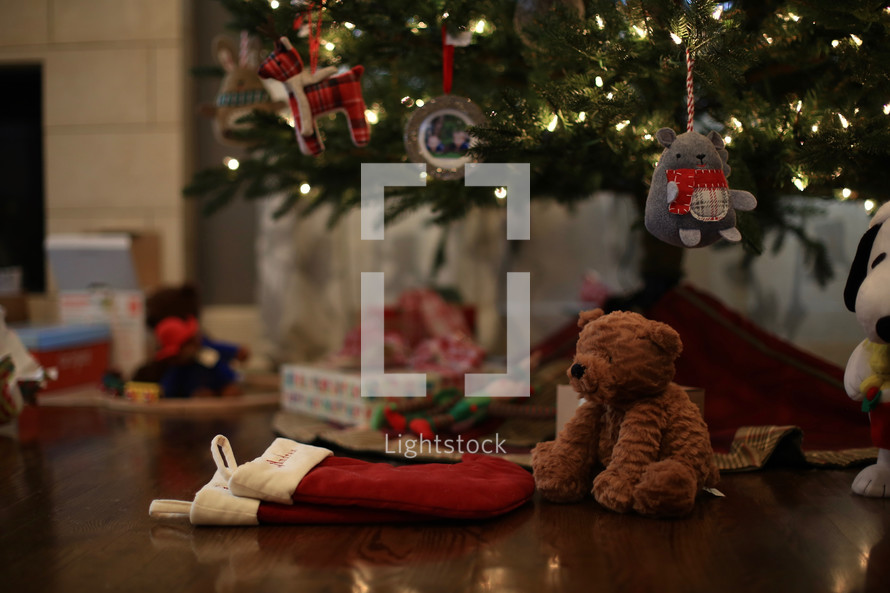 presents, stockings, and teddy bear under a Christmas tree 