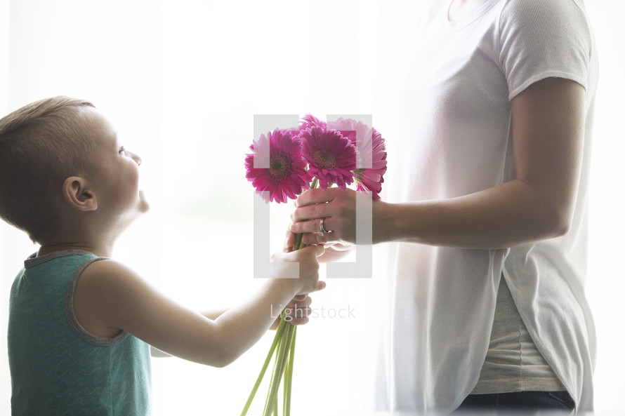 a boy giving his mother flowers for mother's day 