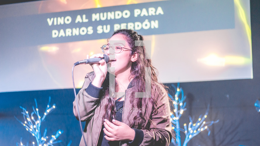 woman holding a microphone and singing during a worship service 