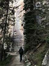 rock cliffs and a man hiking a path 
